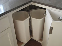 A corner of a kitchen with pullout garbage bins