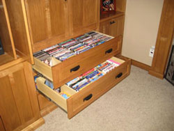 A wooden entertainment center with two drawers of VHS tapes