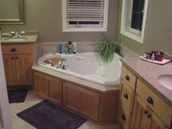 A triangle shaped bathtub with custom wood cabinets