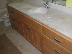 A white swirl granite bathroom sink with wood cabinets