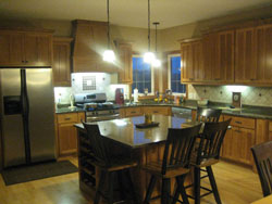 A kitchen with wood cabinets and floors with an island