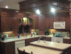 A kitchen with dark cabinetry and a light granite island