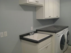 A grey laundry room with white cabinets