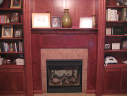 A light red tiled fireplace with a mahogony mantle
