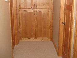 Custom wooden floor to ceiling closets in a carpeted hallway