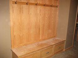 A long wooden coat rack with a bench and storage