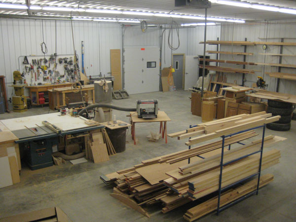 Our organized shop with table saws and racks of wood